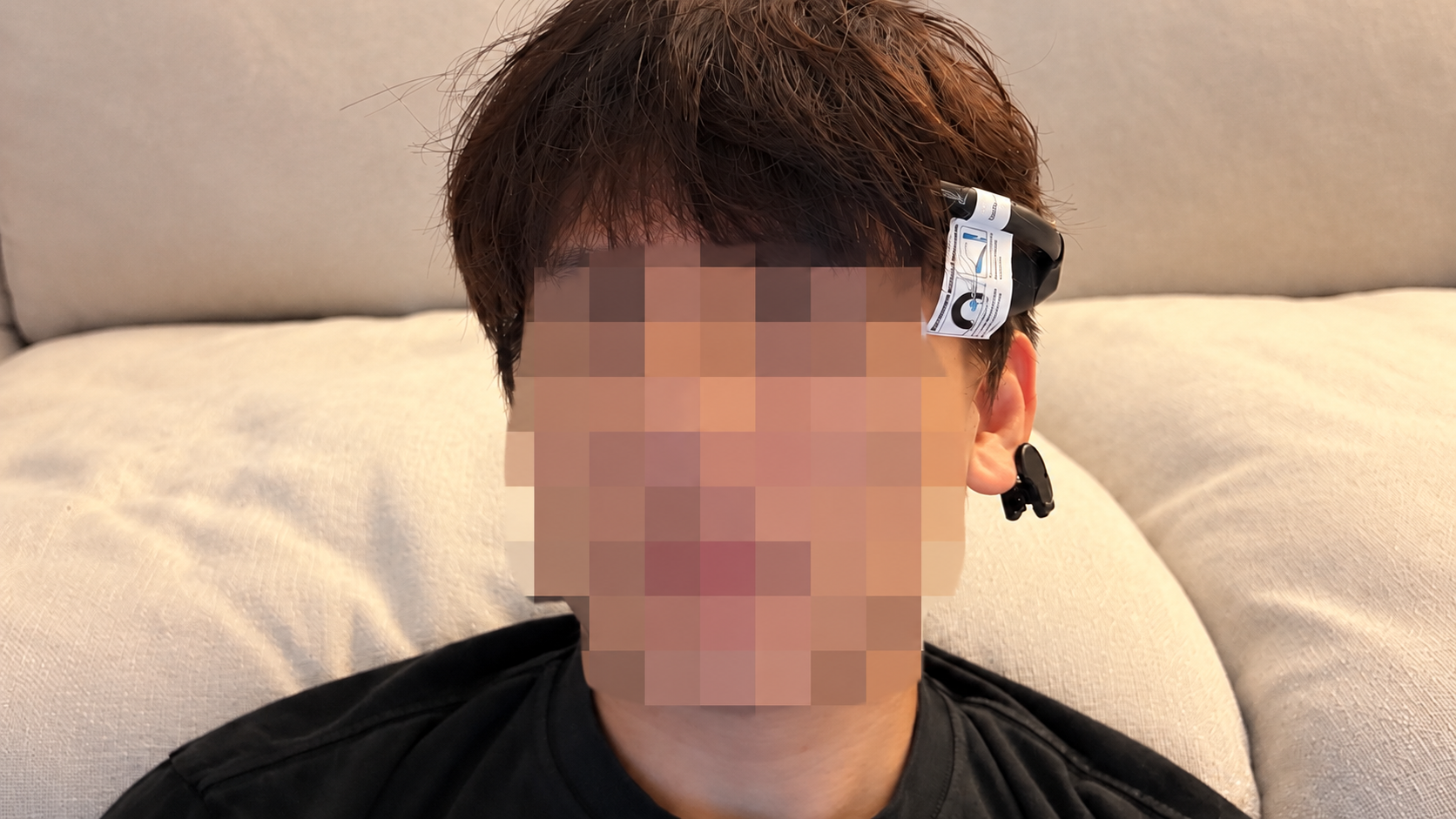 Wearing the forehead sensor and ear clip, with the face pixelated.